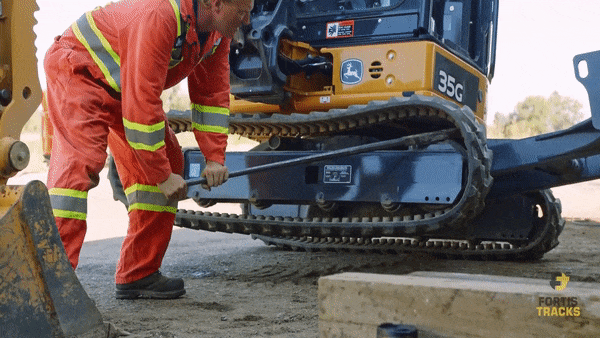 Using a chisel bar, the excavator operator is walking the track forward while Keith remove the track from the sprocket and idler