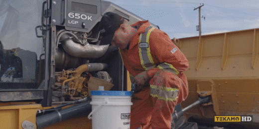 Heavy duty mechanic refills engine oil for a John Deere 650K