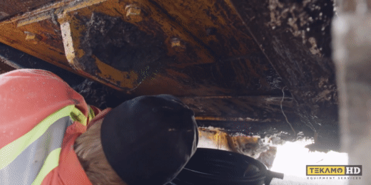 Heavy mechanic demonstrates removing John Deere dozer oil pan