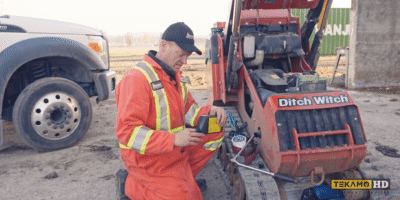 Heaby equipment mechanic installs oil filter on Ditch Witch sk755