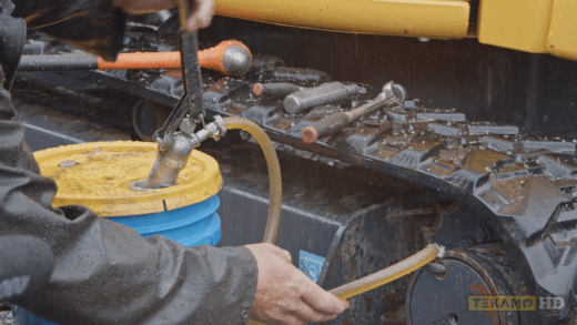 Heavy mechanic demonstrates how to fill the final drive oil on a mini excavator