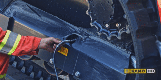 Using a grease gun to tighten the track on a skid steer