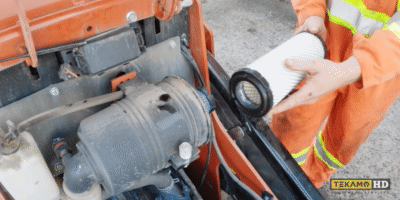 Heavy duty mechanic demonstrates putting a new air filter into a mini skid steer