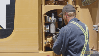 Heavy equipment mechanic removes the oil filter from an excavator