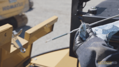Heavy mechanic points to where to check oil levels on a dipstick