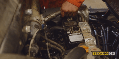Heavy mechanic turning over an engine, bleeding out the air from fuel lines