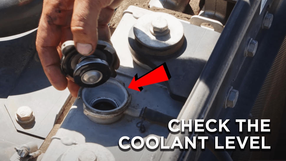 Cap twisted off the coolant tank of a Komatsu excavator and an arrow pointing to it