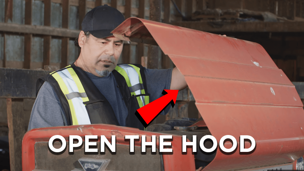 Mechanic opening the hood on a massey Ferguson Tractor