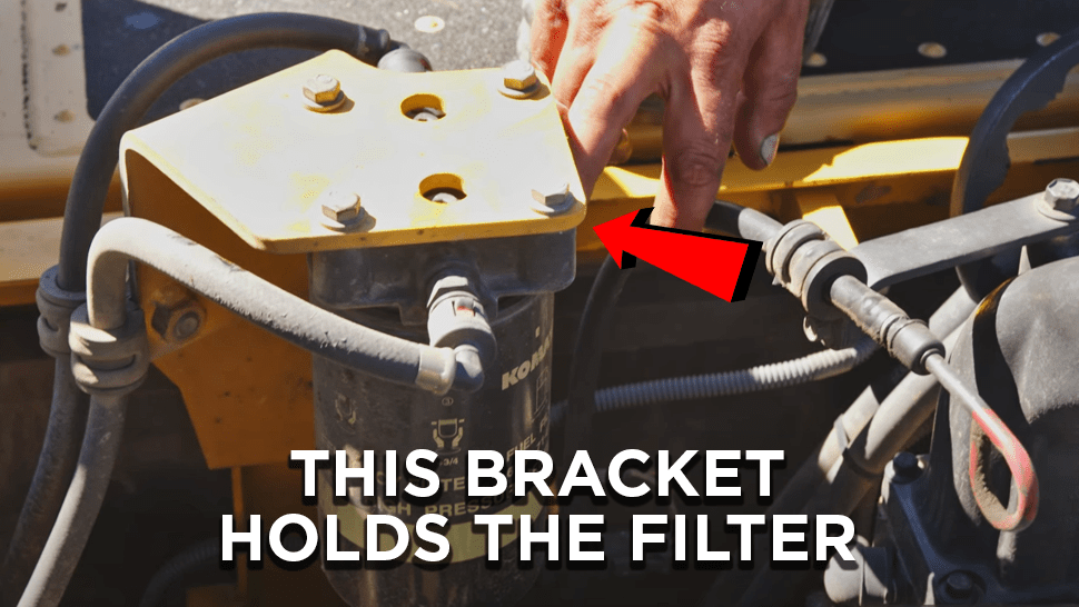 Arrow pointing to where a bracket holds the filter head on a Komatsu excavator